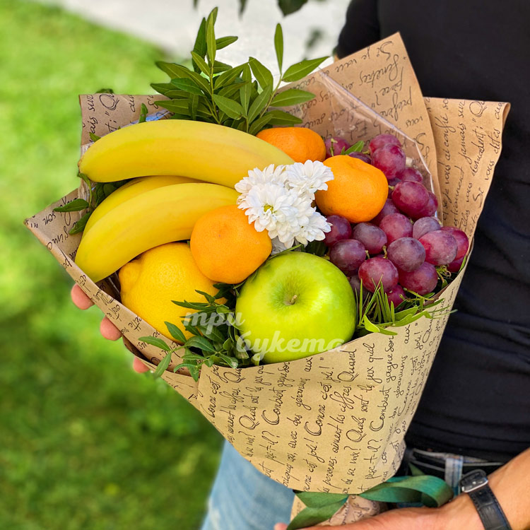 Букет из бананов и мандаринов (на фоне зелени, в руках флориста)